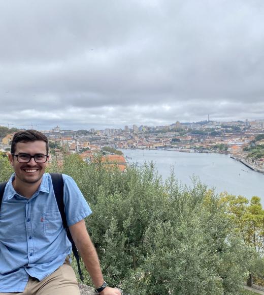 A photo of a man with an old city in the background, and a river