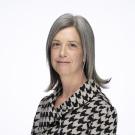 Headshot of middle-aged woman with gray hair in black-and-white houndstooth blouse.
