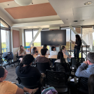 attendees of a presentatin in a sunlit conference room.
