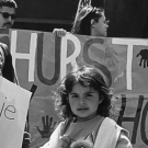 Black-and-white photograph of children holding protest signs in a crowd